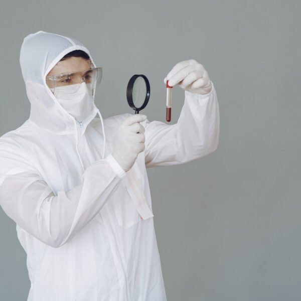 Corona virus theme. Man in a protective suit. Doctor looks at the blood tube.