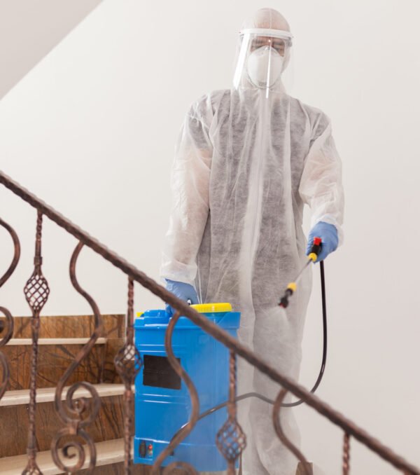Man spreading disinfectant against covid-19 wearing biohazard costume.